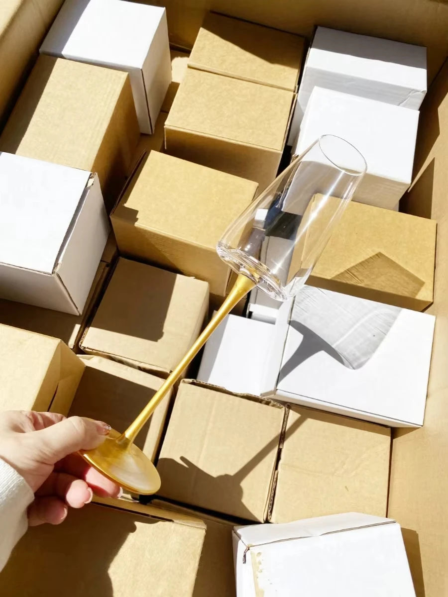 Imagem 4: "Stem & Base" crystal champagne flute in Golden Stem variant displayed on its packaging box — CL House Drinkware collection