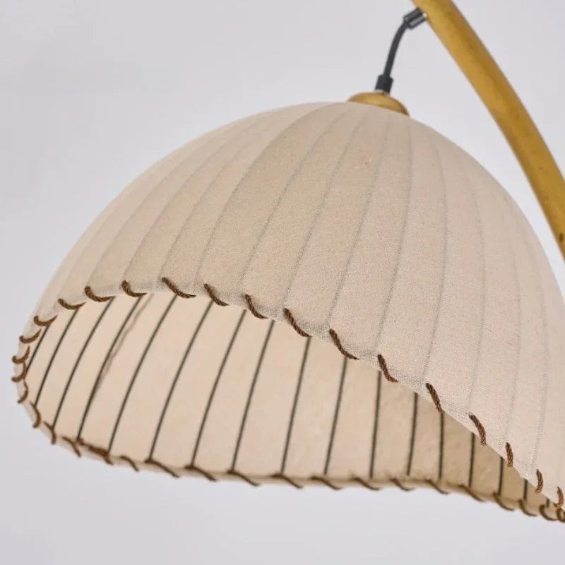 Close-up of the Arc & Pleat pleated canvas lampshade showing the fine vertical pleats, scalloped hem with dark stitching detail, and bamboo-finish arc
