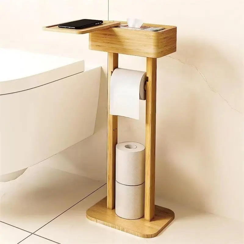 : Freestanding bamboo toilet paper holder with open storage box on top holding a phone, roll holder in the middle and spare rolls stored at the base, white background
