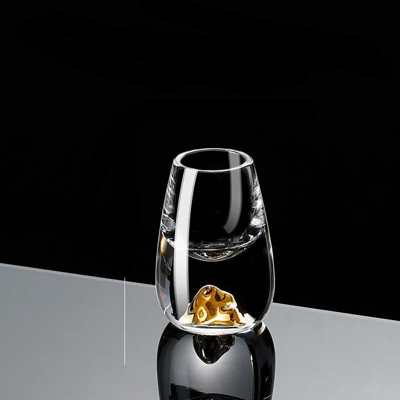 Gold Sculptural crystal shot glass in the Globe design with a gold sphere detail in the base, displayed against a black background.