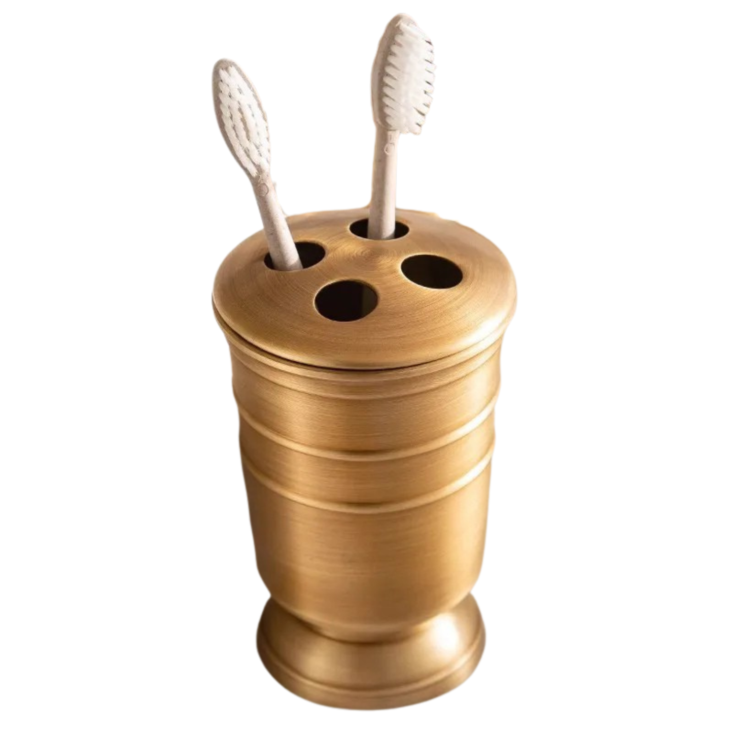 Antique brass toothbrush holder with four slots and ridged cylindrical body, two toothbrushes displayed, brushed warm gold finish, white background