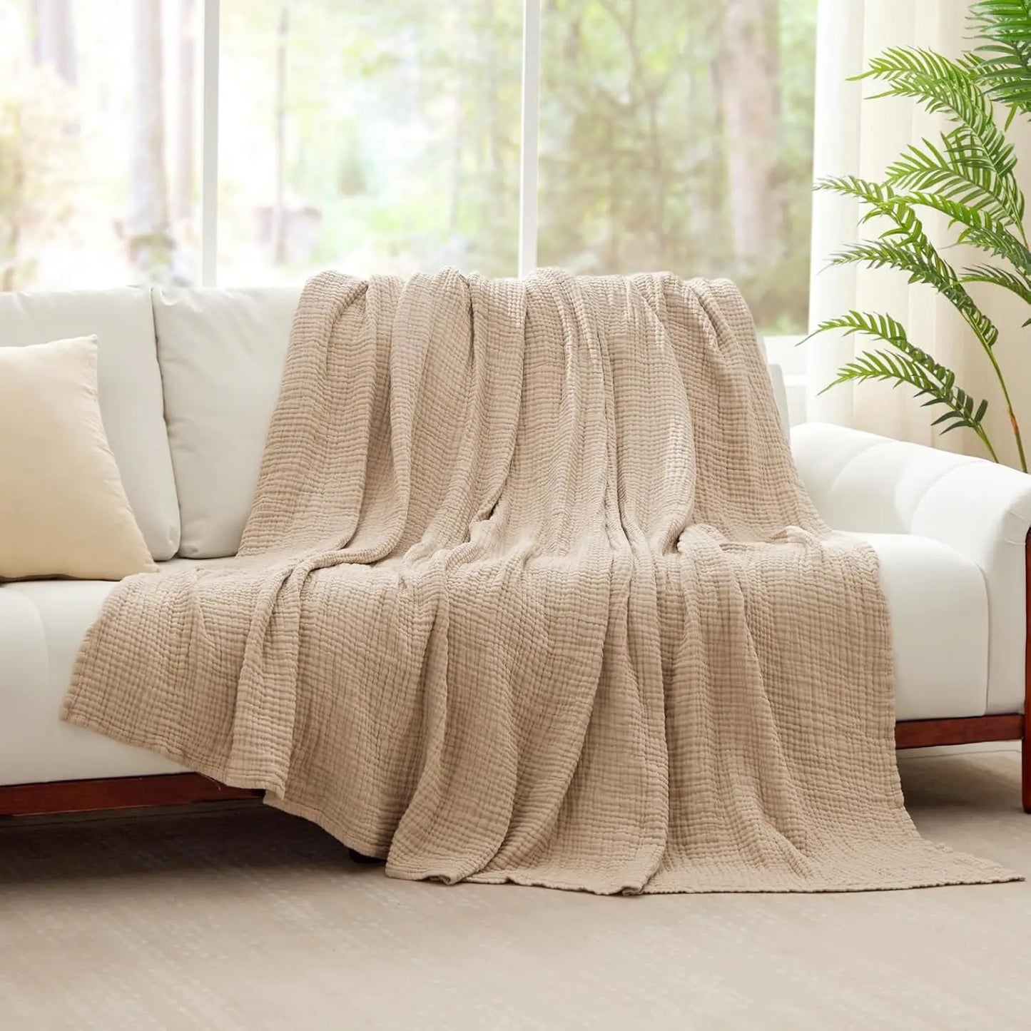Sand Linen 100% cotton 6-layer muslin throw blanket draped over a white sofa in a bright living room
