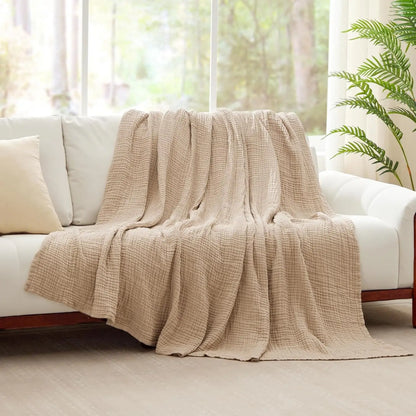 Sand Linen 100% cotton 6-layer muslin throw blanket draped over a white sofa in a bright living room