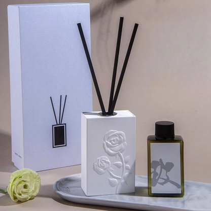  "Lotus Bloom" ceramic reed diffuser — rose-embossed white porcelain with natural reed sticks and botanical styling — CL House