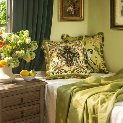 "Tropical Reverie" velvet cushion covers styled on a bed — botanical print and Jungle Sovereign monkey design, sage green bedroom with dark curtains, gold-framed artwork and fresh flowers