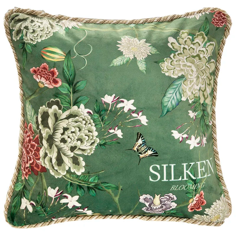 "Garden Silk" velvet cushion cover, Silken Blooming design — deep green ground with lush white and pink peonies, zebra butterfly in flight, white jasmine sprigs and "SILKEN BLOOMING" script, gold braided piping trim