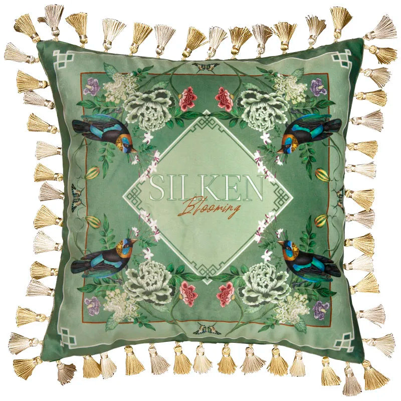 "Garden Silk" velvet cushion cover, Silken Blooming with tassels — sage green ground with four symmetrical exotic birds at corners, white and pink peonies, central diamond frame with "SILKEN Blooming" script, abundant gold and cream tassel trim