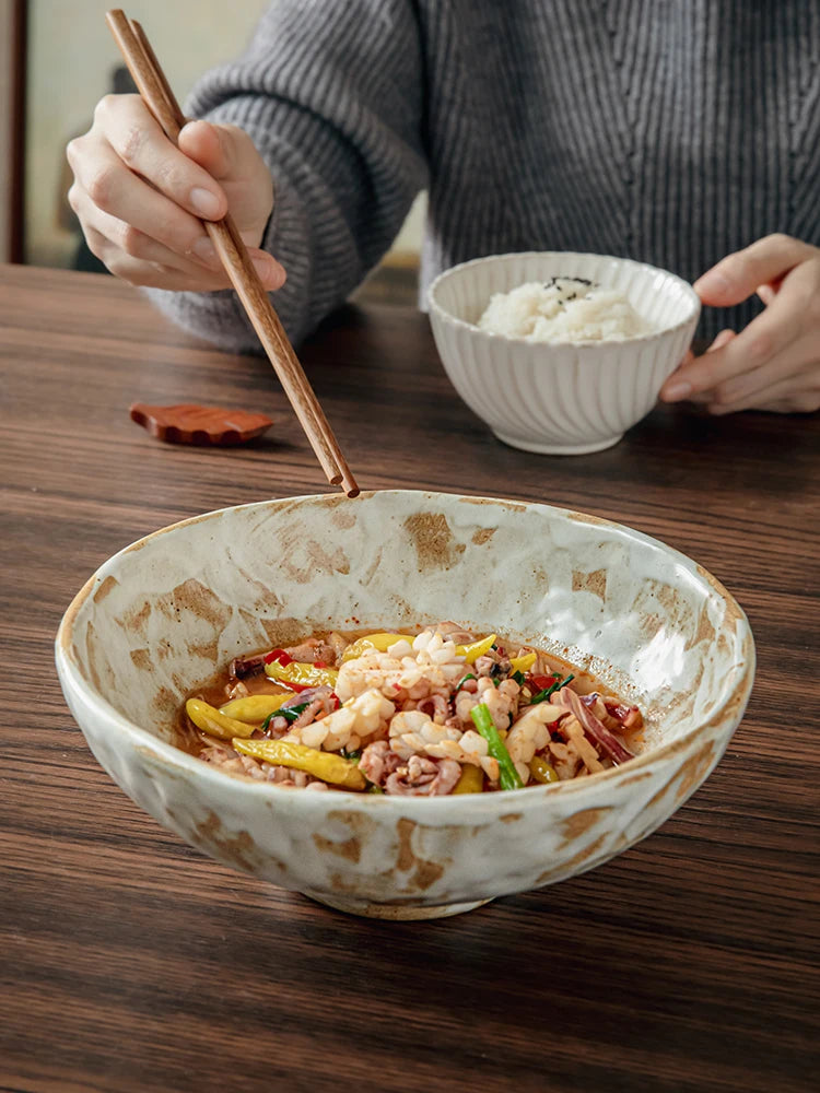 Rustic amber brushstroke ceramic serving bowl filled with Asian noodle dish on dark wooden table, lifestyle dining scene with chopsticks and rice bowl