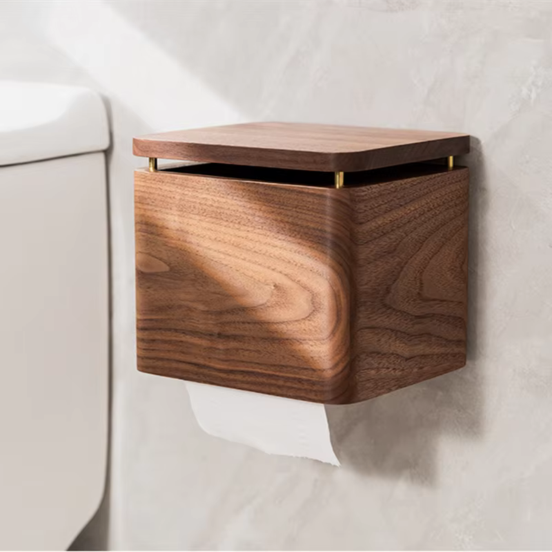  Walnut wood small tissue holder mounted on bathroom wall beside toilet, brass hinge detail, warm walnut grain texture, paper roll dispensing below — japandi bathroom accessory