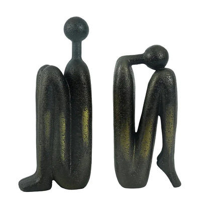 Pair of dark resin abstract human sculptures with elongated forms, shown side by side against a white background.