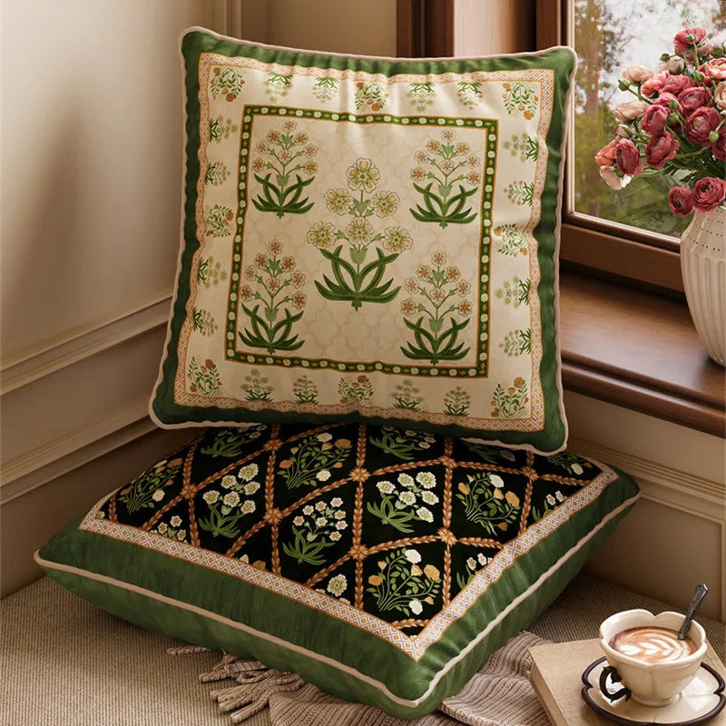  "Ivory Garden" and "Midnight Trellis" Indo-Persian velvet cushion covers by a window — ivory ground with green botanical block print on top, black ground with gold diamond trellis and white florals below, sage green border and cream piping on both — CL House