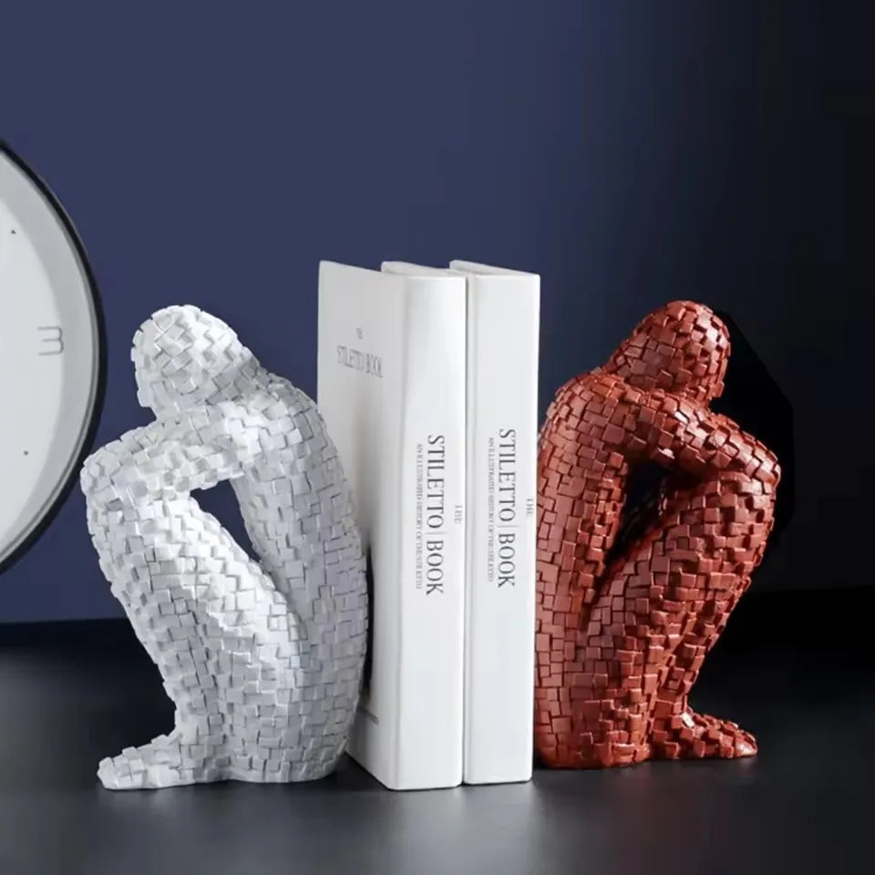 White and red mosaic resin figure sculptures displayed on either side of two books.