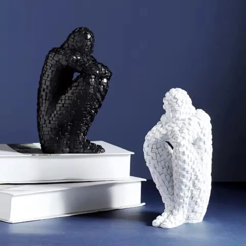 Black and white mosaic resin figure sculptures displayed on stacked books against a blue background.