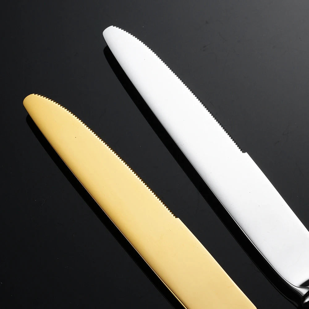 Close-up of "Twisted Rope" dinner knife blades in Gold and Silver finish on a dark surface — showing the serrated edge and mirror-polished stainless steel detail