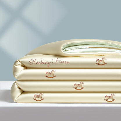  Alt text: "Ice Bloom cooling summer quilt in Rocking Horse — champagne ivory with embroidered rose gold rocking horse motifs and 'Rocking Horse' script detail, mint green reverse"