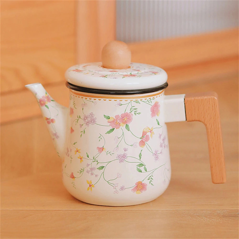 Imagem 6: Floral enamel teapot with wooden handle resting on a warm wooden surface, full side view showing trailing pink and lilac blossom print — Blossom Kettle by CL House