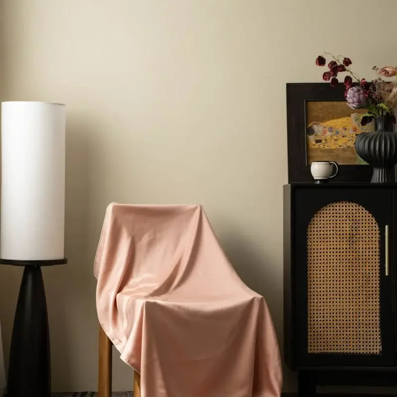 Peach Bloom 100% Tencel cooling summer blanket draped over an armchair in a styled living room