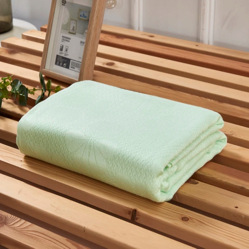 Folded "Aqua Weave" bamboo fibre cooling blanket in Sage Mint neatly displayed on a natural wood slatted bench — lightweight and breathable summer blanket