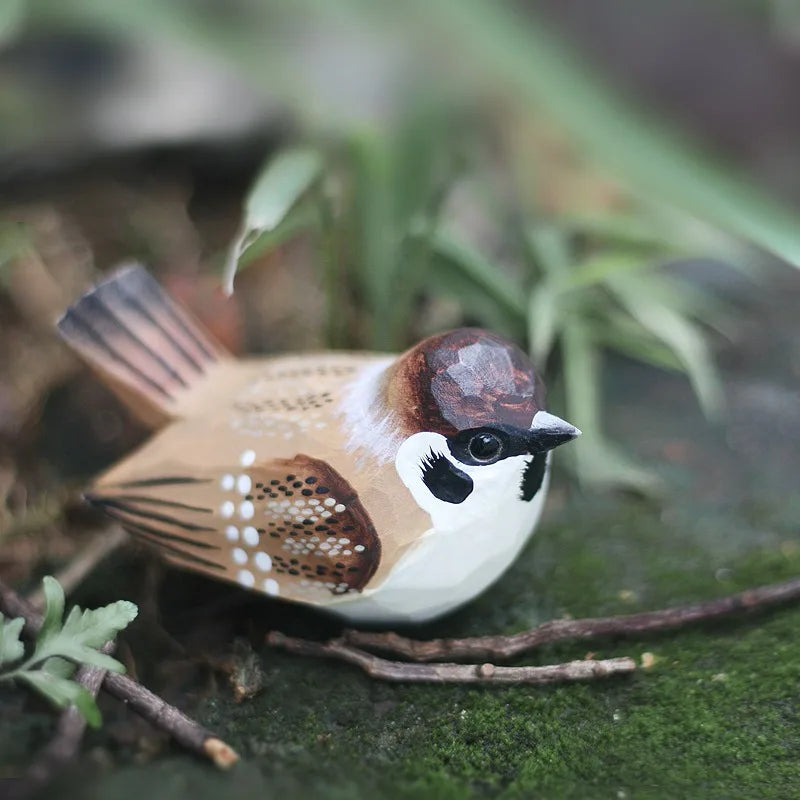 "Little Sparrow" hand-carved wood bird figurine resting on moss among botanical elements, CL House