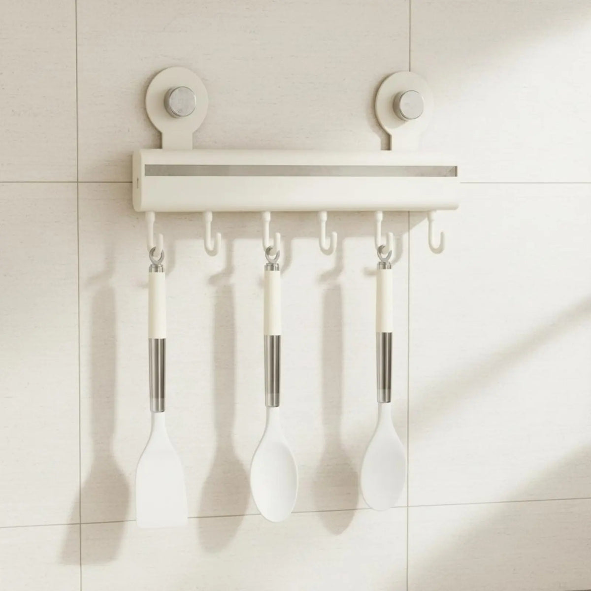 Cream adhesive wall-mounted kitchen hook rail with seven sliding hooks holding white silicone spatula and spoons on white tiles, CL House & Home