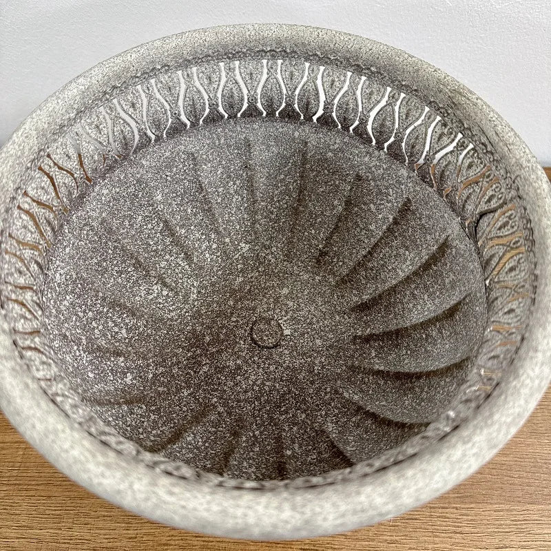 "Roman Urn" ornate stone-texture garden urn planter, top-down view showing spiral fluted interior, drainage hole at centre, acanthus leaf relief border, Stone Grey finish, shown on wooden surface