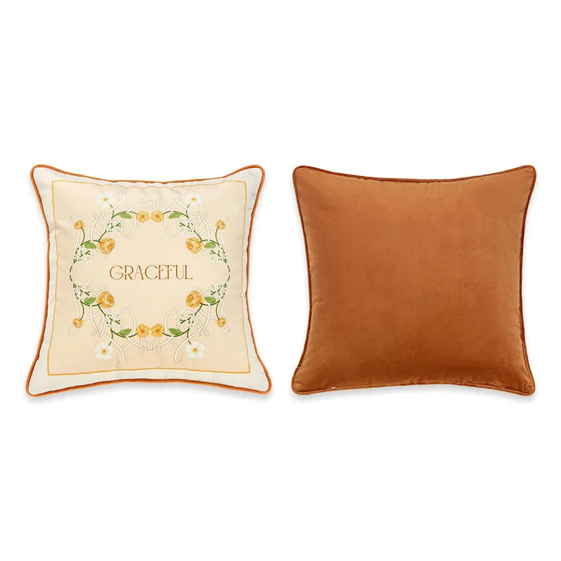 "Graceful" botanical velvet cushion cover front and back view, cream ground with art nouveau wreath of yellow roses and trailing vines, typographic "GRACEFUL" centre, plain caramel velvet reverse with orange piping — CL House Cushions collection