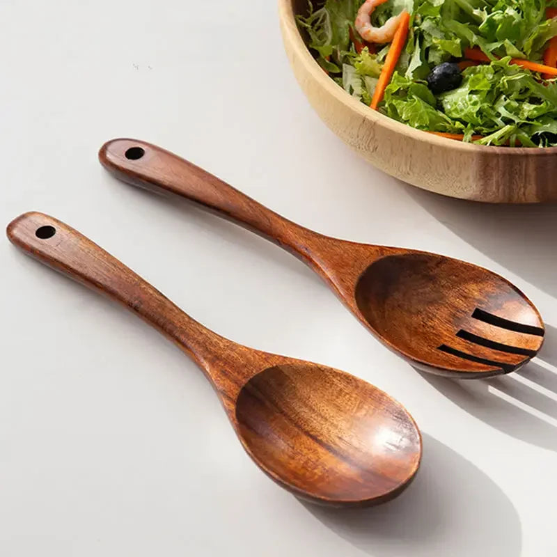 "Wild Harvest" acacia wood salad servers set laid on white surface beside a wooden bowl with fresh salad, natural kitchen styling