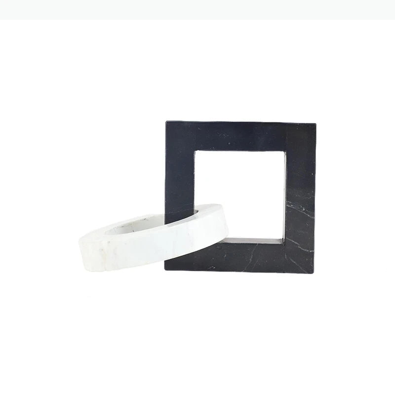 Square black and white interlocking marble sculpture with dimensions of approximately 23.5 by 15 by 15 centimetres.