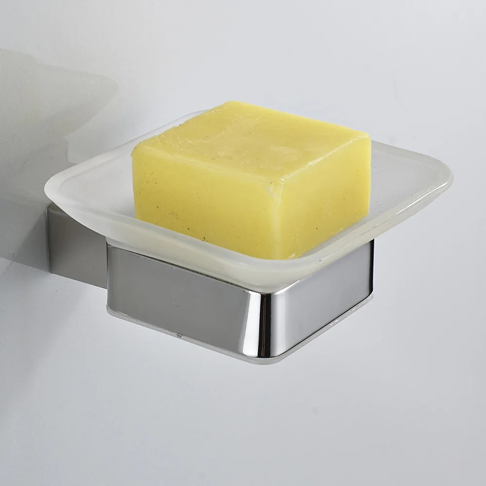 Wall-mounted chrome soap dish with frosted glass tray holding a yellow artisan bar soap, mounted on white wall