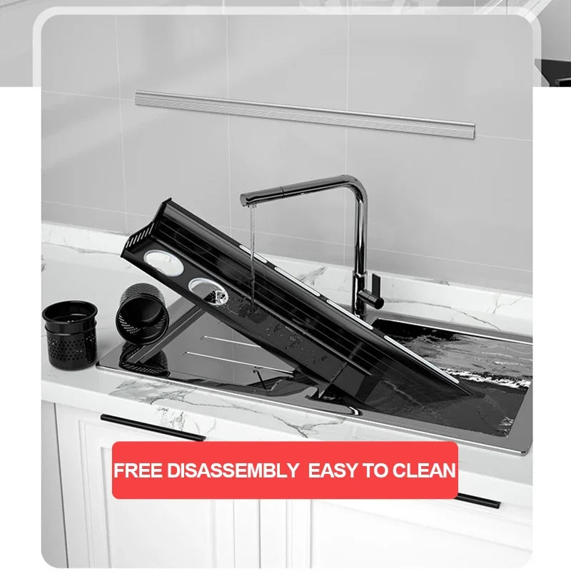  Matte black kitchen shelf disassembled and being rinsed under running water at a kitchen sink — organiser cup and drip basket separated alongside, demonstrating easy disassembly and cleaning maintenance