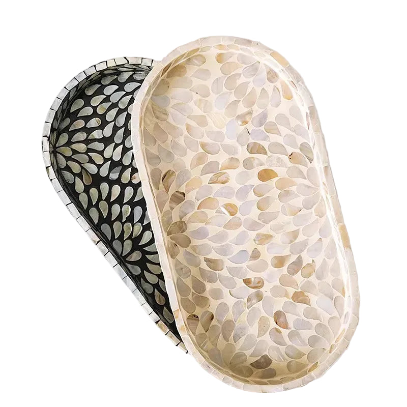 Top view of Pearl and Midnight mother-of-pearl oval trays showing contrasting shell mosaic patterns — cream organic inlay versus black floral radiating design, handcrafted detail — artisan bathroom tray