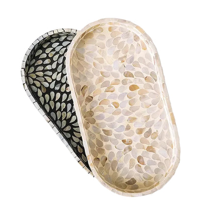 Top view of Pearl and Midnight mother-of-pearl oval trays showing contrasting shell mosaic patterns — cream organic inlay versus black floral radiating design, handcrafted detail — artisan bathroom tray