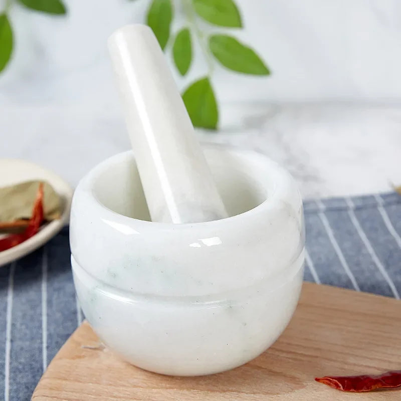 alt text: Pure white marble mortar and pestle viewed from above, pestle laid separately to the left on blue striped linen cloth over a wooden chopping board — smooth polished interior visible, minimalist top-down shot of the Pure White variant of the Stone Grind Mortar & Pestle Set by CL House
