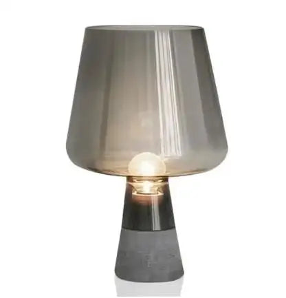 "Smoke & Cement" glass table lamp with smoke grey shade and exposed bulb on a raw cement base, white background