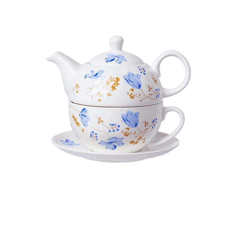 White porcelain tea for one set with blue chicory flowers and gold botanical details, including teapot, cup and saucer stacked together