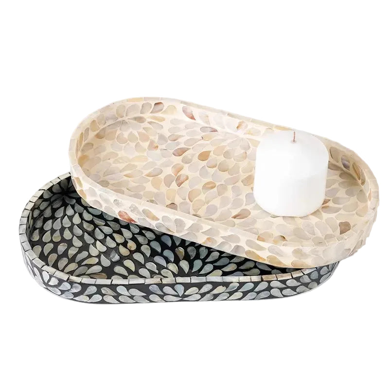 Pearl and Midnight mother-of-pearl oval trays stacked on white background, Pearl shell cream mosaic on top with white pillar candle, Midnight black mosaic below — artisan decorative tray set