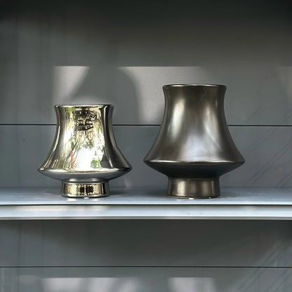 Bell Tower metallic ceramic vases in Silver Small and Gunmetal Large side by side on grey shelf, showing finish contras
