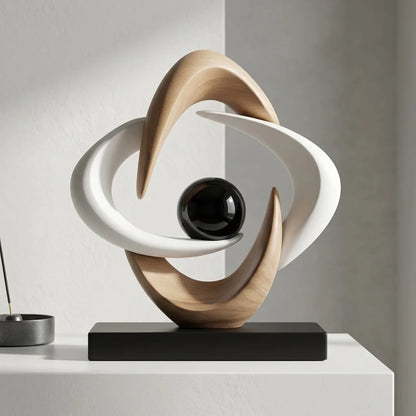 White and gold abstract resin sculpture with flowing interlocking loops and a glossy black sphere on a black rectangular base, isolated against a white background