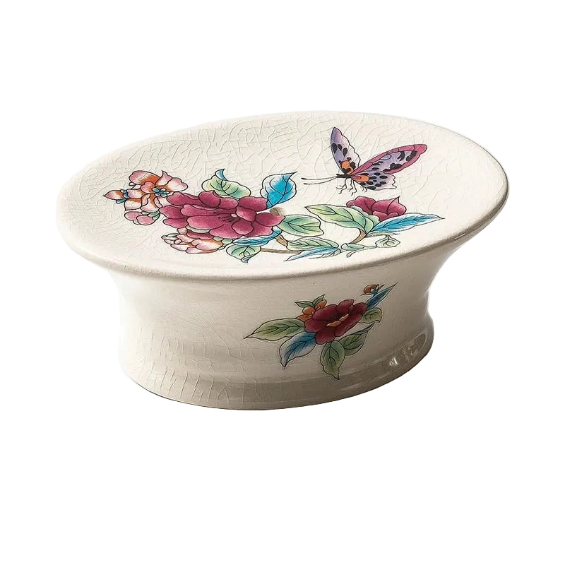 Oval pedestal ceramic soap dish with pink peony and butterfly chinoiserie print, crackle-glaze finish, angled view on white background