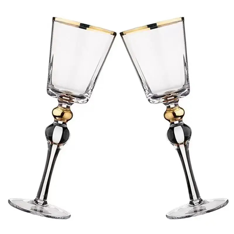 Two "Golden Hour" crystal wine glasses touching rims in a toast, gold filigree detail catching the light — CL House Drinkware collection