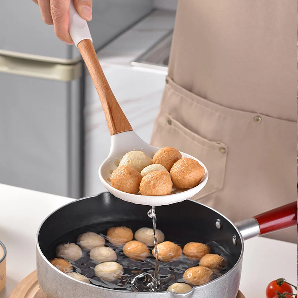 Person using white silicone skimmer spoon with bamboo handle to lift fish balls from a pan, CL House & Home