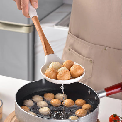 Person using white silicone skimmer spoon with bamboo handle to lift fish balls from a pan, CL House & Home