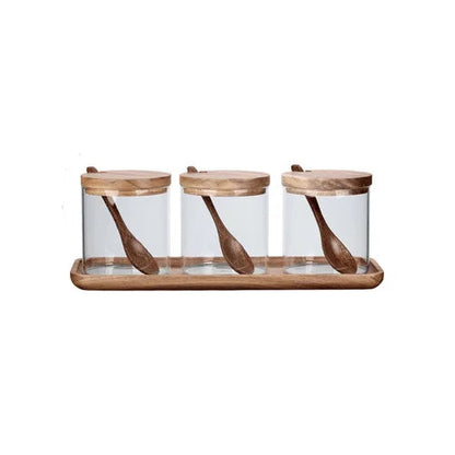  Set of three clear glass spice jars with acacia wood lids and matching wooden spoons, displayed on a rectangular acacia tray, white background — Acacia & Glass Spice Jar Set by CL House