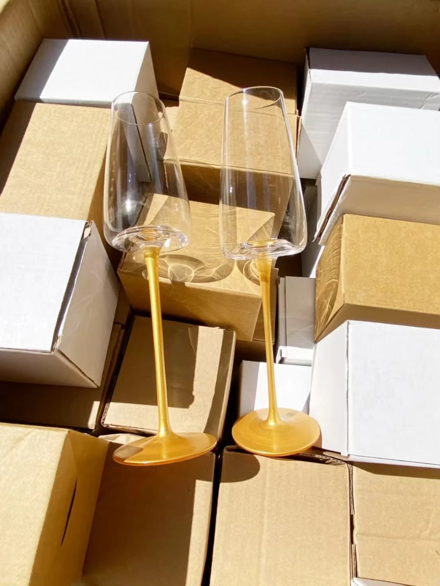 Two "Stem & Base" crystal champagne flutes in Golden Stem variant displayed on their packaging boxes — CL House Drinkware collection