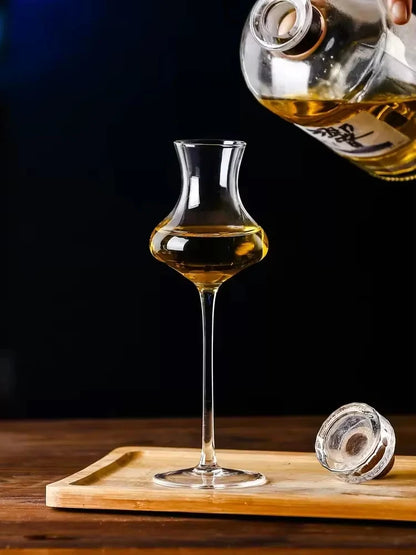  "Slender" crystal spirits glass being poured with wine from a bottle on a table, sleek elongated silhouette — CL House Drinkware collection