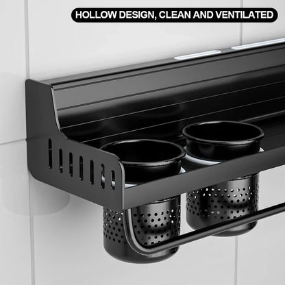 Underside close-up of matte black kitchen shelf showing hollow ventilated design of two organiser cups and perforated drip baskets below — space aluminium construction with slotted side panels and towel bar rail