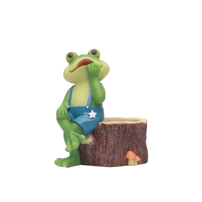  "Frog Tale" resin frog planter in Stump Dreamer — hand-painted frog in blue dungarees seated on a tree stump planter with mushroom detail, white background