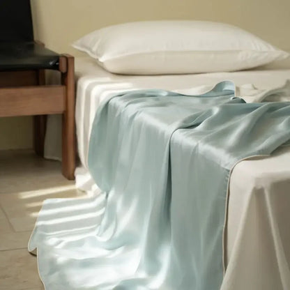 : Mist Blue 100% Tencel cooling summer blanket draped over a bed in a minimalist bedroom