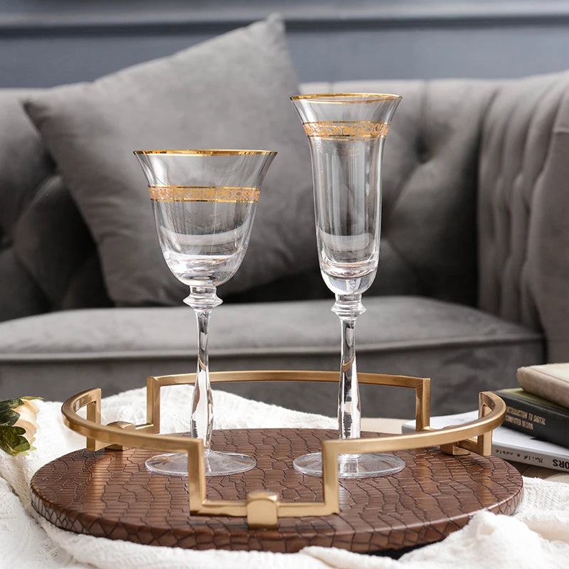  Close-up of gold filigree engraving on crystal champagne flute and wine glass rim, warm lifestyle setting