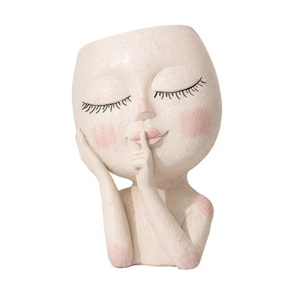 Hush Muse" sculptural face resin planter in ivory cream with closed eyes, rosy cheeks and shh finger gesture, full body view, white background